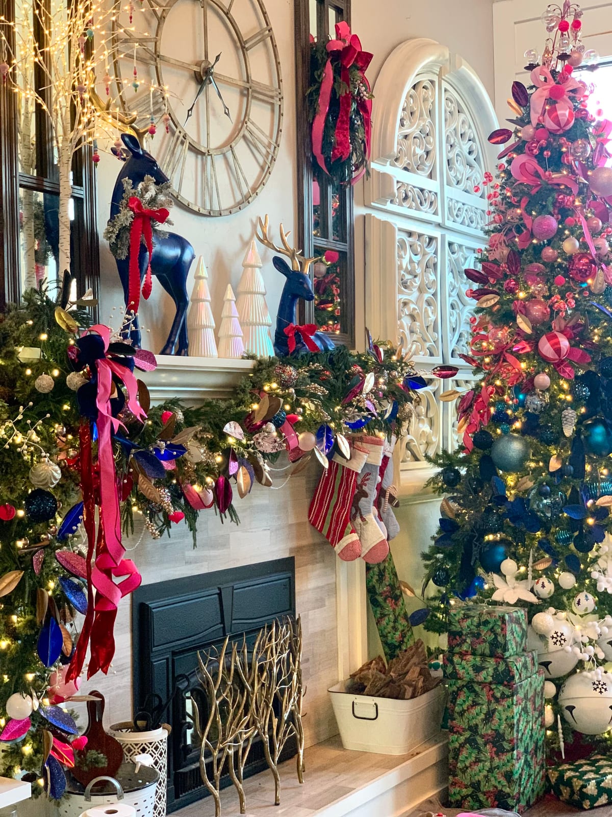 Living room mantel with navy reindeer, evergreen garland in pink and navy ribbon, and a Christmas tree in pink, navy, and white